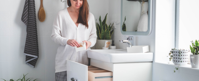 Happy young woman standing near dressing table and taking out a beauty cosmetic from drawer.