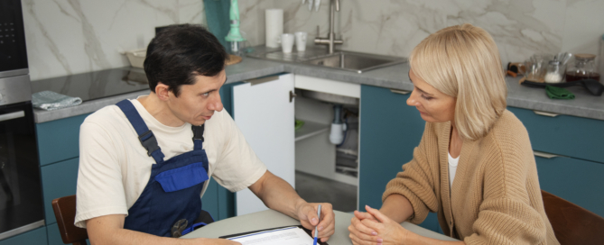 Male plumber working with client fix kitchen problems
