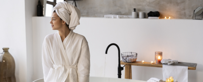 Young woman sitting by bathtub before taking bath